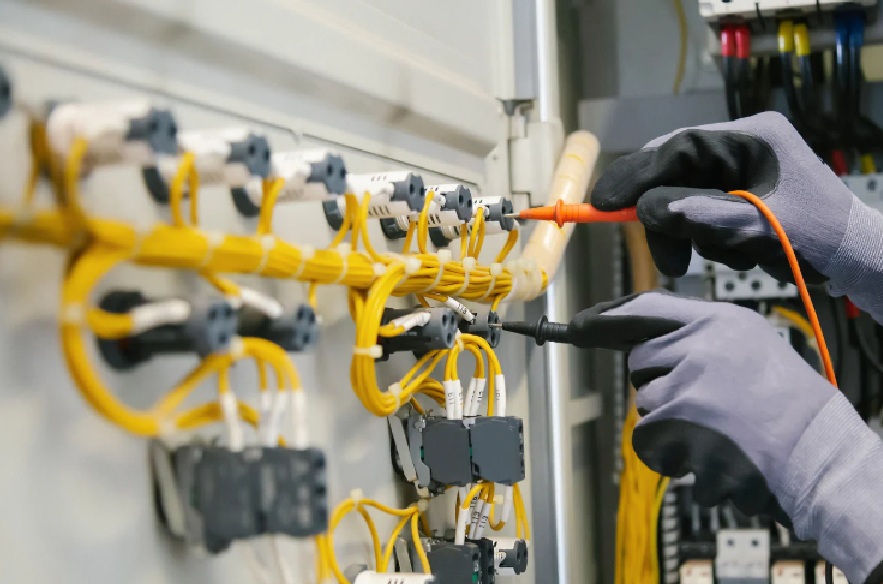 Technician testing wiring in an industrial control panel with a multimeter