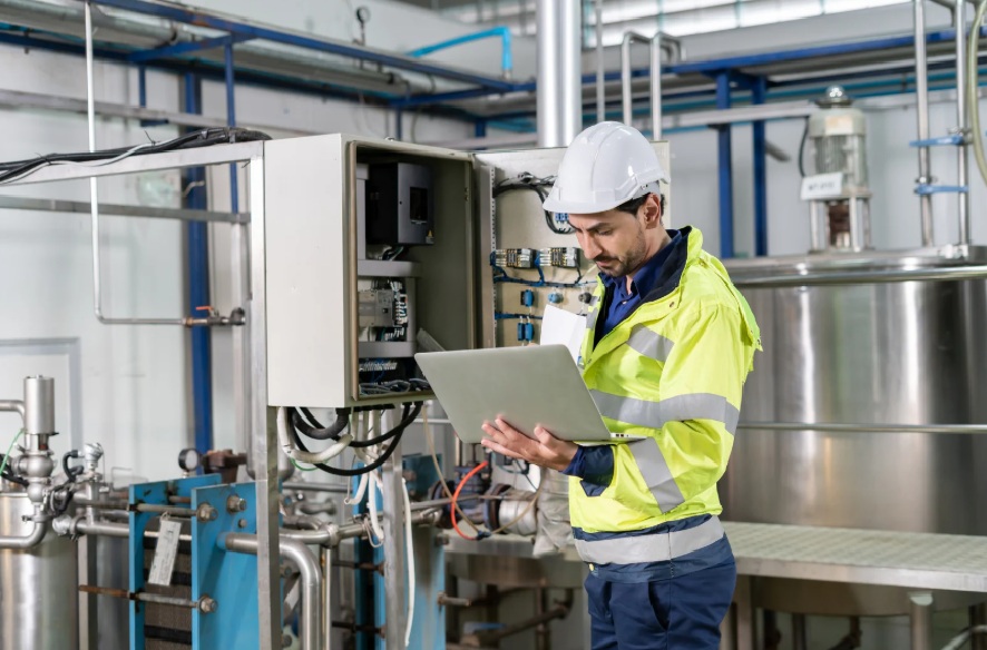 Technician using a laptop to diagnose an industrial control panel