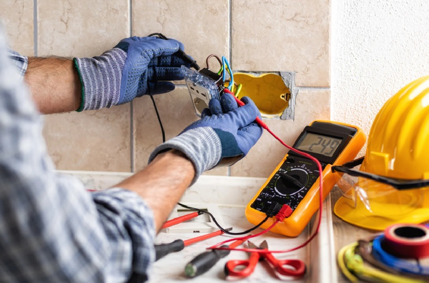 Copper Creek Electric, Goodlettsville - electrician using a multimeter to test wiring behind a wall outlet