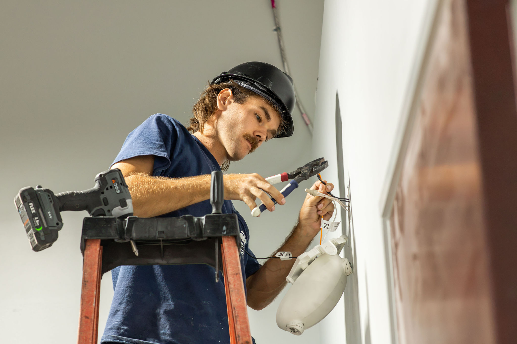 Copper Creek Electric, Goodlettsville - technician installing a wall-mounted light fixture from a ladder