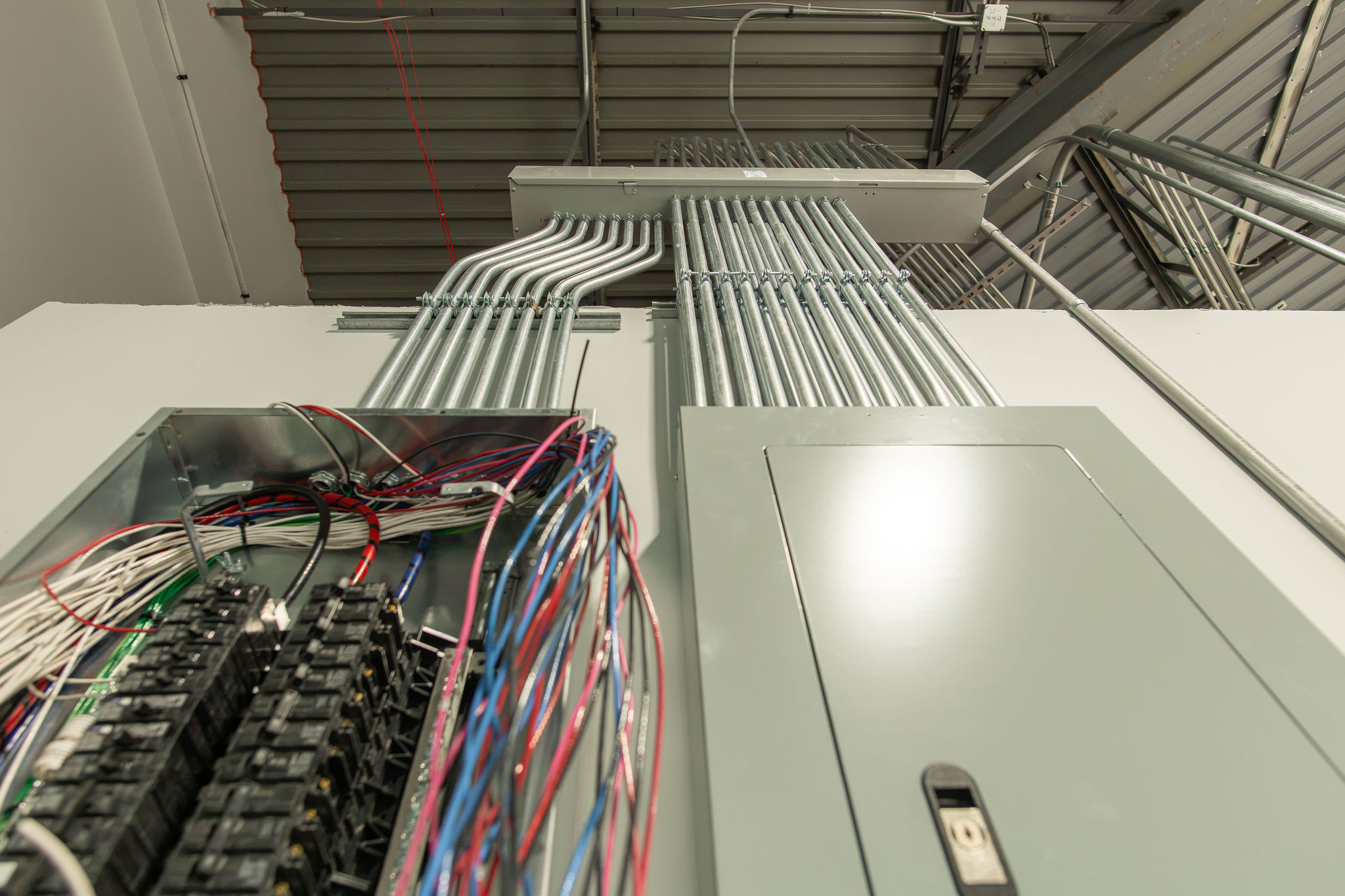 Overhead conduit runs feeding electrical panels in an industrial facility